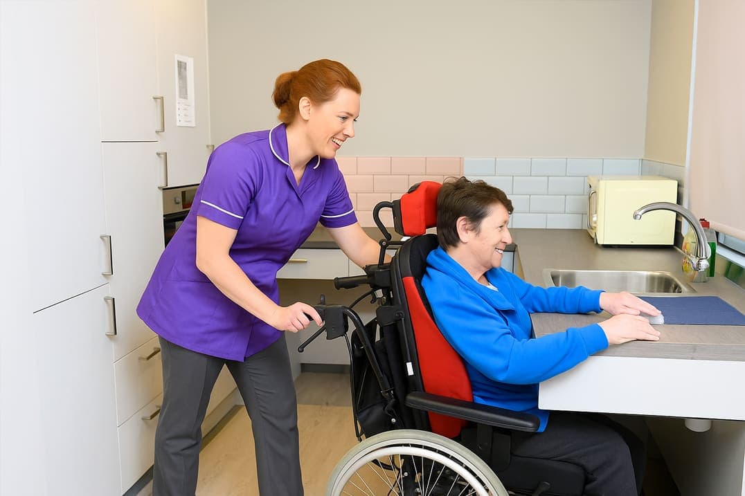 A support worker helping a young adult prepare a meal